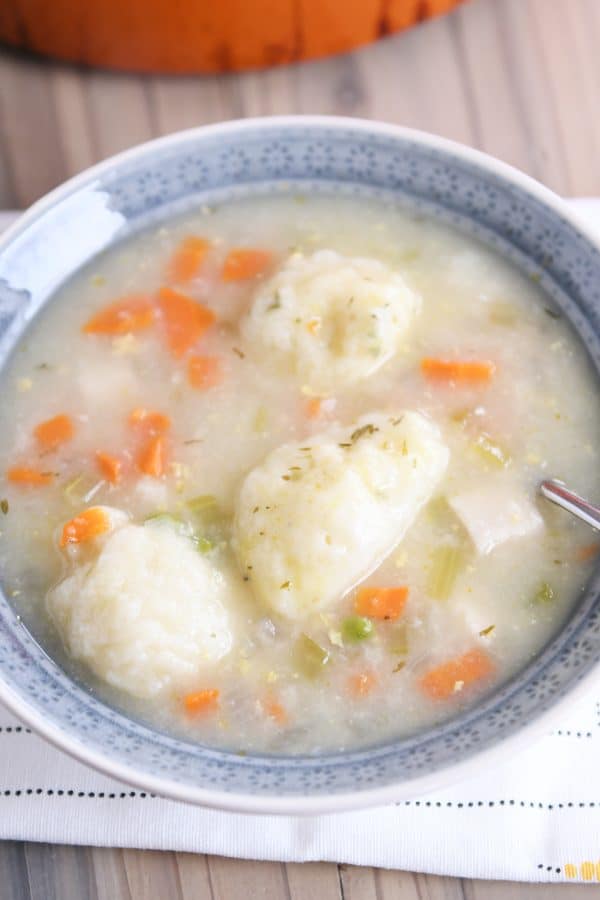 Top down view of blue bowl with chicken dumpling soup.